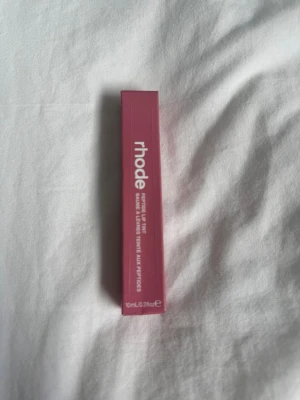 Rhode Peptide Lip Tint läppbalsam/Salty tan - Säljer ett Rhode Peptide Lip Tint läppbalsam i en snygg rosa förpackning. Produkten innehåller 10 ml och är framtagen med peptider för att ge återfuktade och mjuka läppar. Perfekt för dig som vill ha både färg och vård i ett.