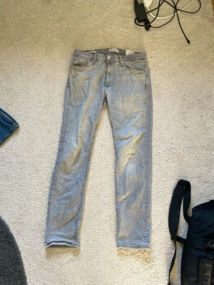 Ljusblå slim fit jeans - Säljer ett par ljusblå slim fit jeans med klassisk femficksdesign och normalhög midja. Jeansen har dragkedjegylf och raka ben. Materialet är mjukt denim i bomull med lite stretch för extra komfort. I storlek 30/32