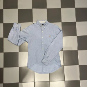 Ralph lauren skjorta - Snygg och stilren Blå Ralph lauren oxford slim fit skjorta. Passar till de mesta och skjortan är i otroligt fint skick, tveka inte att höra av dig om de finns frågor!