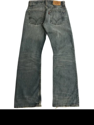 Levi's ljusblå bootcut jeans - Säljer ett par klassiska ljusblå Levi's jeans med bootcut passform och råa kanter nertill. Jeansen har två bakfickor med den ikoniska Levi's-sömmen och en läderpatch i midjan. Perfekta för en avslappnad och trendig look.