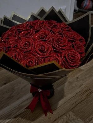 Bukett med glittriga röda rosor - Säljer en stor bukett med konstgjorda röda rosor täckta av glitter. Blommorna är arrangerade i svart och guldigt papper och dekorerade med ett rött band. Perfekt som present eller dekoration.😍🌹
