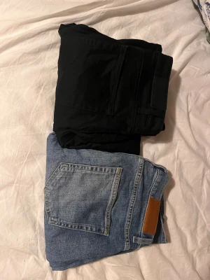 Svarta regular fit jeans Dressmann - Säljer två par ett svart och ett blått par regular fit jeans från Dressmann i storlek 32/32. Klassisk femficksmodell med knappgylf och diskreta sömmar. Perfekta till en avslappnad men ändå stilren look.  400 för ett av paren 800 för båda.