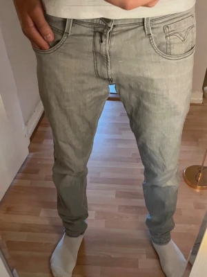 Ljusgrå replay Anbass  jeans  - 34 l 32 Säljer ett par ljusgrå replay  slim fit jeans med modellen är ca 180 klassisk femficksdesign och normal midja. Jeansen har en enkel look utan slitningar och är perfekta för en clean och stilren outfit. Materialet är mjukt och stretchigt för extra komfort.