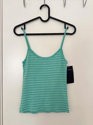 Brandy Melville - En teal randig topp från Brandy Melville, one size. PS, prislappen har tagits av men den har aldrig använts.