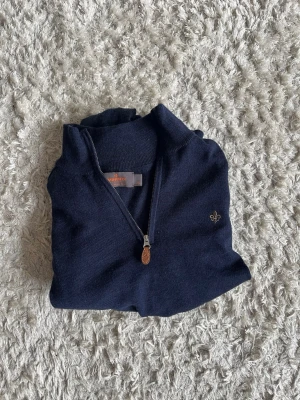 Mörkblå halvzip tröja med brodyr - Mörkblå stickad tröja från Morris det är en modell me halvzip i kragen. Fungerar utmärkt till finare tillfällen