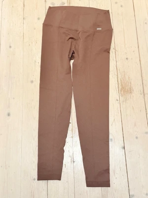 Bruna sömlösa leggings från Aim’N - Snygga bruna leggings från Aim’N med hög midja och sömlös design. Materialet är stretchigt och har en diskret struktur som ger en modern look. Perfekta för en trendig och bekväm stil.