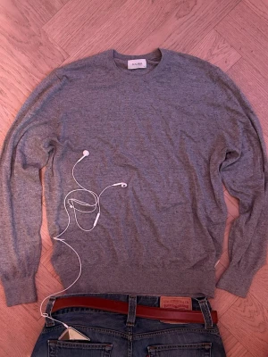 Grå stickad tröja från Scalpers - Size L fits M. Silk and cotton. Säljer en stilren grå stickad tröja från Scalpers med rund halsringning och diskret logga broderad på bröstet. Tröjan har långa ärmar och ribbade muddar vid ärmslut och nederkant. Perfekt till jeans eller chinos. 