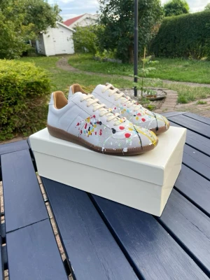 Maison Margiela - Säljer dessa riktigt snygga gatsen i storlek 43! Skorna är gjorda i skinn och mocka. Skorna har färgen ”White paint splatter” och är i mycket fint skick! Hör av er ifall ni har några frågor eller liknande! ⭐️