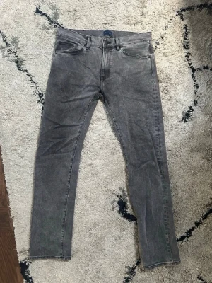 Grå tvättade slim fit jeans - Snygga grå jeans med tvättad look och smal passform. Klassisk femficksmodell med knappgylf och raka ben. Jeansen har en modern vibe och passar perfekt till en avslappnad streetstyle. Materialet är denim i bomull.