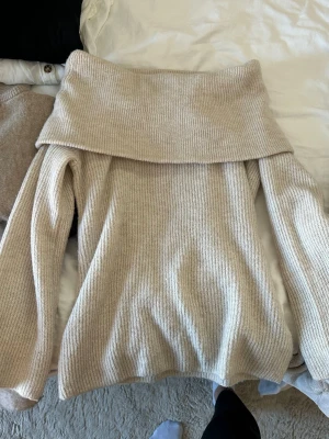 Beige off-shoulder stickad tröja - Säljer en beige stickad tröja med bred off-shoulder krage och långa ärmar. Tröjan har ribbad struktur och är endast använd 1 gång ❤️❤️