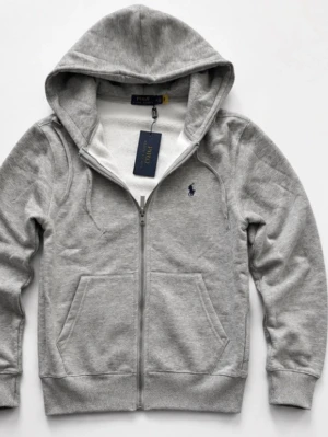 Grå hoodie från Polo Ralph Lauren - Snygg grå hoodie från Polo Ralph Lauren med dragkedja framtill och två stora fickor. Klassisk huva med dragsko och den ikoniska lilla loggan broderad på bröstet. Tillverkad i mjukt bomullsmaterial som är perfekt för chill dagar.