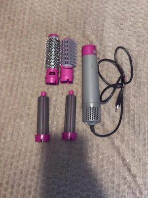 Multistyler för hår med flera tillbehör - Säljer en multistyler för hår i grått och rosa med fyra utbytbara tillbehör: två rundborstar i metall och plast samt två locktillbehör. Perfekt för att skapa olika frisyrer och stylingeffekter. Elektrisk med sladd och enkel att använda.