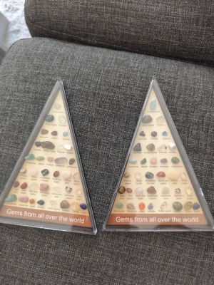 Gems from all over the world - 2 st This is a triangular display case containing labeled samples of various gemstones from around the world. The second image provides a close-up view of some of the stones and their labels.
