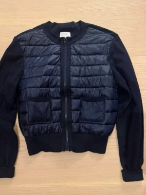 Mörkblå quiltad cardiganjacka - Snygg mörkblå cardiganjacka med quiltad framsida och två framfickor. Jackan har dragkedja framtill, ribbade muddar och ärmar i mjukt tyg. Perfekt för lager på lager och en stilren look. Storlek 170 men passar vuxen S