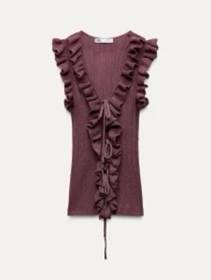 Rödlila ärmlös topp med volang och knyt - Supersöt lila topp med djup v-ringning, volangdetaljer längs kanterna och knyt framtill. Ärmlös modell i mjukt material som ger en romantisk vibe. Perfekt att styla med jeans eller kjol för en trendig look.