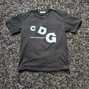 Svart CDG t-shirt  - Tja, säljer nu denna feta Comme des Garçons PLAY T-shirt 🖤 Storlek M och i fint skick. Riktigt clean svart t-shirt med den klassiska CDG PLAY-designen framtill. Enkel men ändå riktigt fet och passar till typ allt.  Tveka inte på att höra av dig vid fler frågor eller funderingar 😁