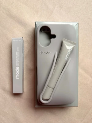 iPhone 17,17pro,16,16pro,15pro,14,13 Grått mobilskal Rhode med tubhållare - iPhone 17,17pro,16,16pro,15pro,14,13 available. GRAY color. Snyggt och stilrent grått mobilskal från Rhode med smart hållare för tub, perfekt för läppbalsam eller liknande. Skalet har en mjuk, matt finish och är designat för att passa moderna smartphones. Rhode-loggan är diskret präglad på baksidan.