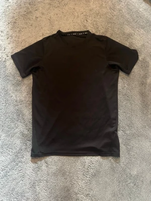 PUMA svart träningströja T-shirt  - Säljer en svart kortärmad träningströja från Puma. Tröjan har rund hals och är tillverkad i ett lätt och funktionellt material som passar perfekt för olika typer av sportaktiviteter. Väll använt plagg men fortfarande i väldigt bra skick!