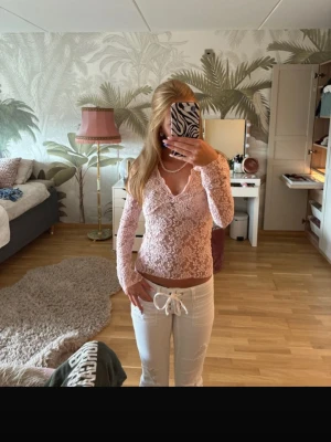 Ljusrosa spetsblus med v-ringning från Gina-Tricot - Supersöt slutsåld ljusrosa blus i spets med v-ringad hals och långa ärmar. Blusen är lite mer tight i moddelen och genomskinlig samt lite vidare ärmar. Säljer då den aldrig kommit till användning. 