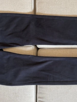 Mörkblå randiga jeans från Armani - Säljer ett par mörkblå jeans med tunna vita ränder och snygga kontrastsömmar. Jeansen har klassisk femficksmodell, dragkedja och knapp framtill. Tillverkade i ett stretchigt material för extra komfort. Perfekta för dig som gillar en stilren men ändå unik look.