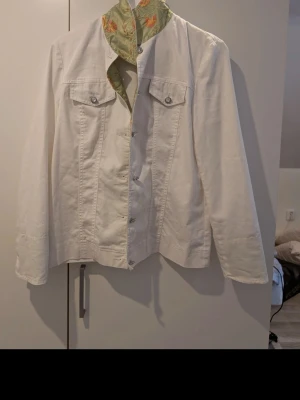 Unikt, vit set med blommigt foder - Stilren vit jeansjacka från M.Asam med raka linjer och två bröstfickor med knappar. Insidan har ett unikt ljusgrönt foder med blommigt mönster som ger en cool kontrast. Perfekt för dig som vill sticka ut med detaljer. Set storlek 40 båda, passar någon som är 170 lång. Med klassisk krage och två bröstfickor med knappar. Rak passform och knappstängning framtill. Perfekt för dig som vill sticka ut lite extra.