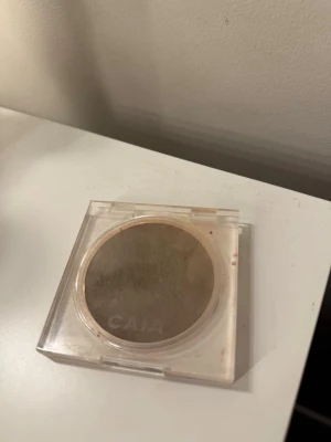 CAIA Soft Melt Bronzing Balm - Bronzer från CAIA i färgen Soft Melt. Kommer i en rund, kompakt plastförpackning med transparent lock. Pudret har en varm, brun ton som ger en naturlig solkysst look. Perfekt för att skulptera ansiktet och addera glow.
