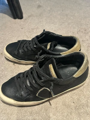 Philippe model skor  - Svarta Philippe model skor med guldiga detaljer, perfekta skor till sommaren å de är väldigt sköna! Några skavanker där fram med de är ingenting som börjar öppna sej å bli större, hör av er vid frågor❤️