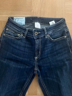 Mörkblå jeans från Dondup - Snygga mörkblå jeans från Dondup med fransiga benslut och kontrastsömmar. Klassisk femficksmodell och stretchigt denimtyg. 