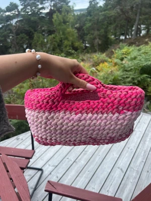 Handvirkad rosa handväska - Supersöt handväska i handvirkat material med olika nyanser av rosa. Väskan har en rektangulär form och inbyggda handtag💕💕