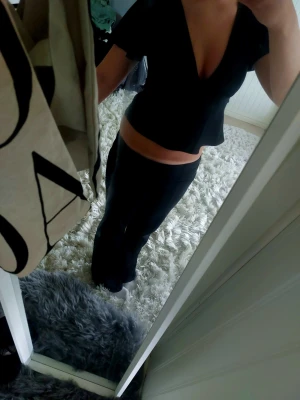 Svart croppad v-ringad topp - Snygg svart croppad topp med djup v-ringning och korta ärmar från Gina. Toppen har ett band i midjan som kan knytas för extra detalj i ryggen. Perfekt till höga jeans eller kjol för en trendig look. Säljer pågrund av att den är i det minstaste laget.
