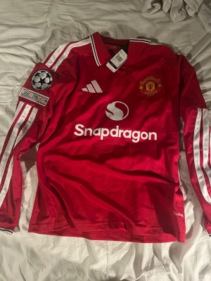 Manchester United S - Säljer en röd longsleeve Manchester United matchtröja från Adidas med Champions League-patch på ärmen. Tröjan har tryck med 'MAINOO' och nummer 37 på ryggen samt. Storlek S men passar M. Pris kan diskuteras.