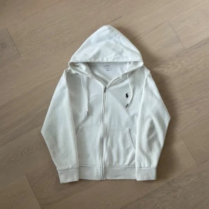 Ralph Lauren hoodie vit - Vit Ralph Lauren-hoodie säljes, storlek S. Skick 8/10 – lätt använd med mindre tecken på slitage på ytan, men fortfarande i fint skick. Klassisk och stilren hoodie av hög kvalitet som passar perfekt till vardags. 📦 POSTAS INOM 24 TIMMAR! Skicka gärna ett meddelande vid intresse eller frågor.