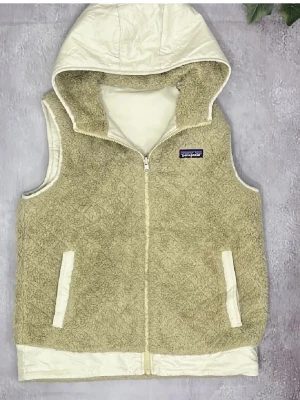 Patagonia Väst - Sjukt sällsynt vintage Patagonia fleece väst. Man kan ha den både med biege päls och vänder man ut och in på den så får man en fin vindväst i krämvit. Skicket på västen bra, inga defekter. Storlek M. Kan möjligtvis byta och även gå ner i pris