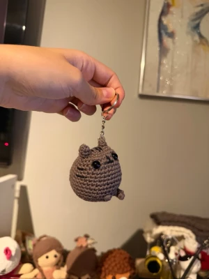 Handvirkad Pusheen nyckelring  - Söt handvirkad nyckelring i form av Pusheen-katten. Perfekt att hänga på väskan eller nyckelknippan för en gullig touch. Tillverkad i bomullsgarn metallkedja och fylld med polyestervadd.