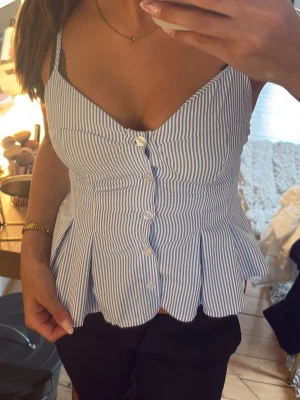 Blåvit randig linnetopp med knappar - Snygg blåvit randig linnetopp med knappar framtill och smala axelband som även är justerbara!!! Storlek XS endast använd 1 gång!