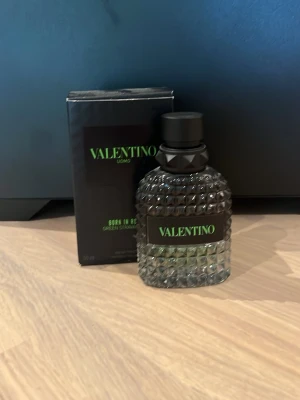 Valentino Uomo Born In Roma parfym - Säljer en Valentino Uomo Born In Roma parfym med cool, nitat glasflaska och svart lock. Flaskan har en modern design med gröna detaljer och etikett. Kommer med originalkartong i svart med grön text. Perfekt för dig som gillar exklusiva dofter. 50ml flaska men är ca 20 ml kvar🙌🏼