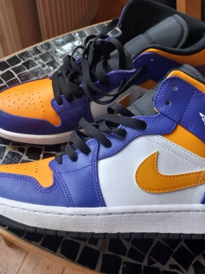 Nike Air Jordan sneakers lila orange och vit - Snygga Nike Air Jordan i lila, orange och vitt med svart snörning. Skorna har den klassiska loggan på sidan och är tillverkade i läder med textildetaljer. Stl 43, endast provade en kort stund utomhus. 