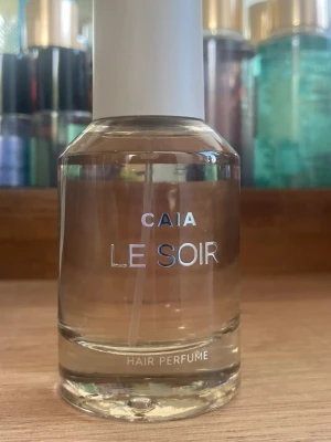 CAIA Le Soir Hair Perfume 50 ml - Fräsch och elegant hårparfym från CAIA i modellen Le Soir. Kommer i en genomskinlig glasflaska med vit kork och silverfärgad text. Perfekt för att ge håret en lyxig doftboost när du vill känna dig extra fräsch.