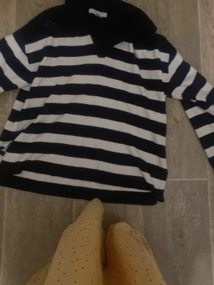 Svartvit randig tröja med krage - Säljer en svart och vit randig tröja med lång ärm och hög krage. Tröjan har breda horisontella ränder och en avslappnad passform. Perfekt för en chill och stilren look.