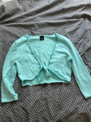 Vintage bolero turkos teal s.Oliver - Säljer denna supersöta turkosa boleron med trekvartsärm från s.Oliver🪽 Boleron har pärldetaljer och knyte framtill och är i storlek 36. Passar även 34 eller xs💗  Priset är förhandlingsbart, men buda inte om du sen inte köper om jag accepterar!  Jag skickar snabbt!