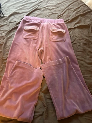 Ljuslila juicy byxor med fickor - Säljer ett par ljuslila juicy byxor i storlek M dem är aldrig använd ute och knappt inne. Så helt som ny. 