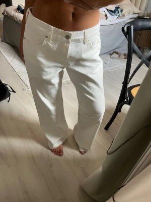 Vita raka jeans med mid waist från NAKD - Säljer ett par vita jeans med rak passform och hög midja. Materialet är kraftigt denim i bomull och de har en clean look utan slitningar eller detaljer. Jag har klippt byxorna men har ej använt dom! Byxorna passar bra för någon som är 160-165 cm lång