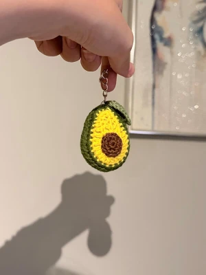 Avokado nyckelring beställning - Handvirkad nyckelring i form av en avokado. Helt ny och virkas på beställning. Små variationer kan förekomma eftersom varje nyckelring är handgjord.