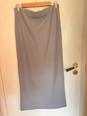 Grå lång kjol med slits bakom - Väldigt enkel och fin kjol, aldrig använd endast privat ett par gånger. Kjolen har ett resår vid midjan.