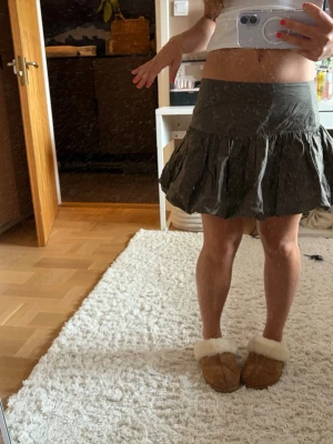 Snygg puffkjol - Kort kjol i mörkgrått med bred linning och volang nedtill. Kjolen har en luftig och flowy passform som ger en avslappnad men ändå trendig look. Perfekt att styla med en crop top eller stickad tröja för en cool vibe.