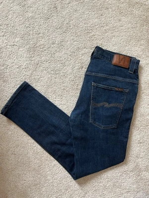 Mörkblå Nudie Jeans - Ett par riktigt feta jeans ifrån märket Nudie Jeans. Storleken är 34-32 och modellen är Thin Finn. Jeansen är som nya utan defekter! Skriv ifall du vill att jag ska skicka fler bilder hur de sitter på!  😁✌🏼 ——————————————————————————                                                    📐| Storlek: 34-32                                                  👖| Märke: Nudie jeans                                         🔎| Skick: Fint skick!                                              💵| Ny Pris: 1699kr