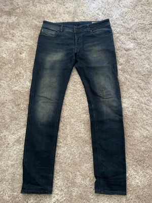 Disel jeans - Säljer ett par mörkblå slim fit jeans med snygga slitningar på låren och klassisk femficksmodell. Jeansen har normal midja och raka ben. Perfekta till en avslappnad stil och passar till det mesta i garderoben.