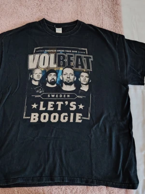 Volbeat tour t-shirt svart - Säljer en svart Volbeat t-shirt från European Arena Tour 2016 med tryck fram och bak. Framsidan har bandmedlemmarna och texten 'Let's Boogie', baksidan har Stockholm-datumet. Perfekt för dig som gillar rock och bandmerch. Materialet känns som bomull.