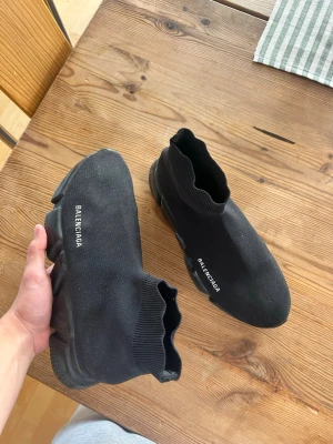 Balenciaga Speed Trainer svarta sneakers - Svarta Balenciaga Speed Trainer sneakers med stickad ovandel i stretchigt tyg och tjock, mönstrad sula. Strumpmodell med ribbad kant och vit Balenciaga-logga på sidan. Perfekta för dig som gillar en clean och modern look.