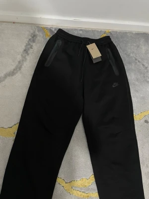 Nike Tech sweatpants  - Säljer mina Nike Tech sweatpants i storlek M. 🩶  De har en lite mer baggy/avslappnad passform och sitter väldigt bra. Perfekta till en clean Nike Tech-outfit eller bara till vardags.  Säljer dem eftersom jag inte längre använder dem.
